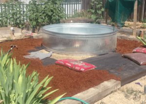 How to Create a DIY Stock Tank Pool: Laying weed mat and bark around base of pool