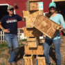 May 2019: Two people standing beside a stack of bee boxes