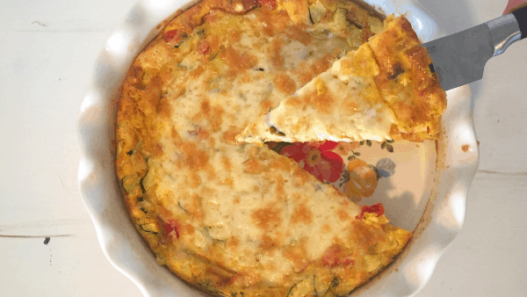 make ahead freezer quiche: quiche in pie pan with one piece being lifted out