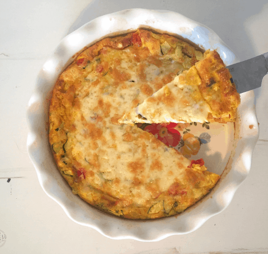 make ahead freezer quiche: quiche in pie pan with one piece being lifted out