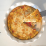 make ahead freezer quiche: quiche in pie pan with one piece being lifted out