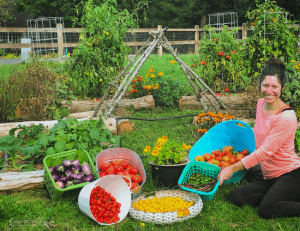 Woman sitting in front of garden beds with baskets full of produce