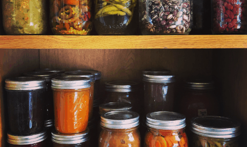 two shelves with a variety of canned foods in jars