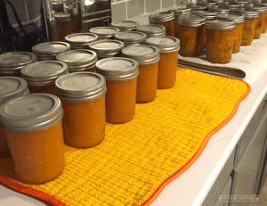 Rows of orange canned food sitting on towels on a kitchen counter