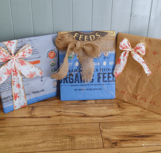 Three presents sit on a wood floor. The presents are wrapped in feed bags and tied with Christmas ribbon