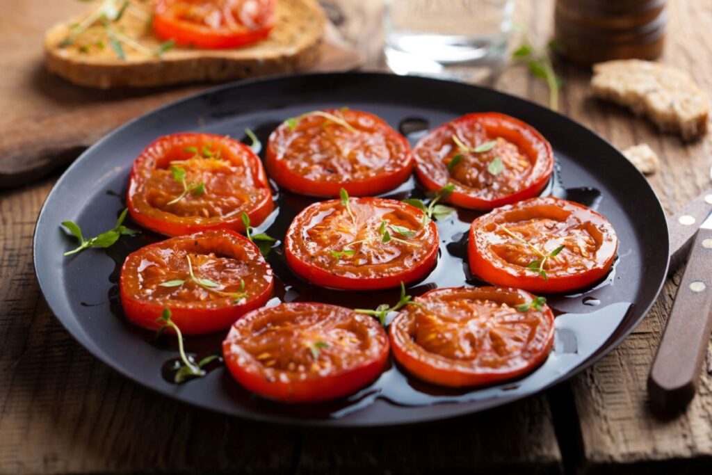 sliced beefsteak tomatoes, drizzled in oil and herbs on a skillet