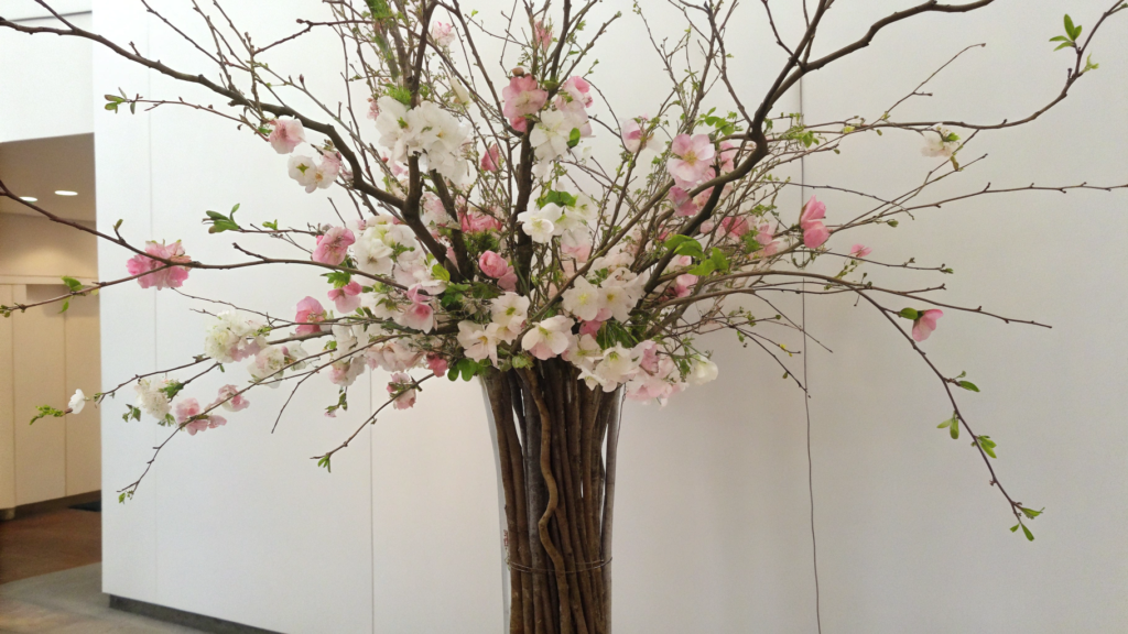 Tall vase arrangement with branches and floating blooms